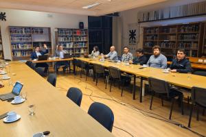 Reunión de trabajo en una sala de la UTN con varias personas sentadas alrededor de una mesa larga.