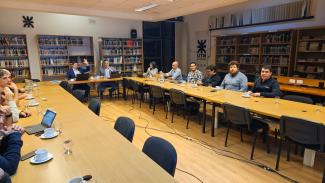 Reunión de trabajo en una sala de la UTN con varias personas sentadas alrededor de una mesa larga.
